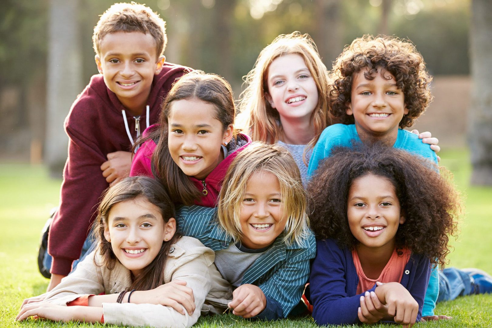 Group Of Children Lying On Grass Together In Park